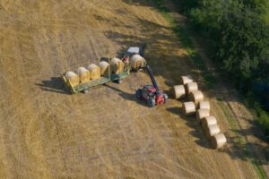 Aerial view of tractor collecting straw bales
