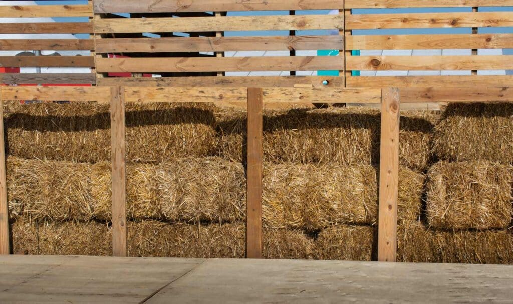 Hay bales stacked forming a wall next to a wooden enclosure