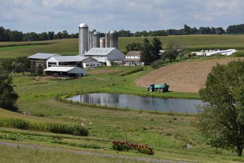 Scenic view of field by the farm against sky