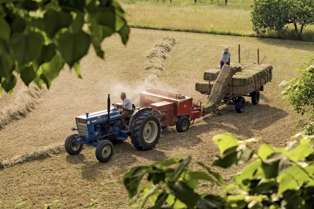 Farmers on Tractor baling hay